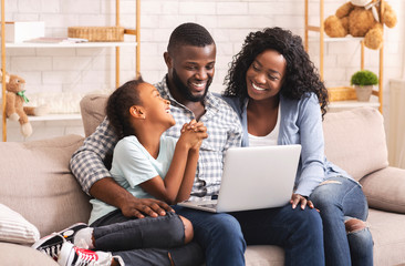 Happy african family watching movie on laptop at home together