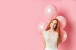 Portrait of smiling happy lady with long hair auburn, air balloons on pink background. People concept