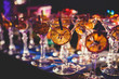 © tsuguliev - View of alcohol setting on catering banquet table, row line of different colored alcohol cocktails on a party, martini, vodka, and others on decorated catering bouquet table event