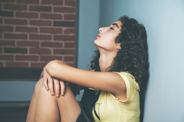 Wall Mural - young sad woman sitting on dark background