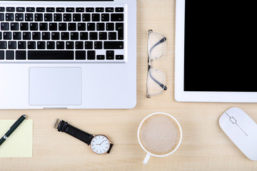 Tablet, laptop computer with glasses, mouse and cup of coffee on wooden table