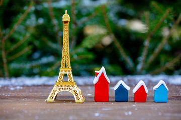 Wall Mural - Golden eiffel tower souvenir and little houses on table with spruce on background