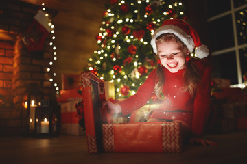 Wall Mural - happy laughing child girl with magic gift on christmas eve.