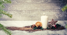Burning Candle From Advent In Front Of Vintage Background And Decorative Christmas Background In Snow