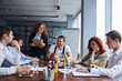 © alfa27 - Personable business colleagues wearing formal wear gathered to discuss business project on table. Flipchart behind, laptops, pencils on table.
