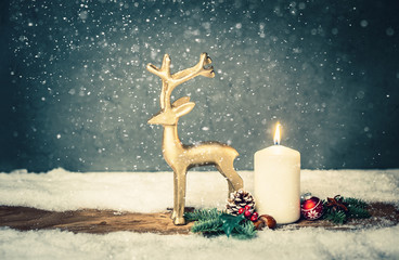 burning candle from tadvent in front of vintage background and decorative christmas background in snow