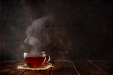 Cup of hot tea with a steam on dark background
