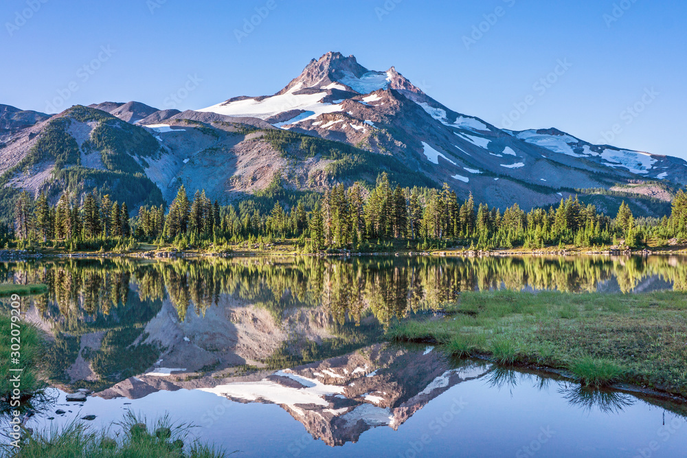 Volcanic mountain in morning light reflected in calm waters of lake.  - obrazy, fototapety, plakaty 