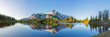 Leinwandbild Motiv Volcanic mountain in morning light reflected in calm waters of lake. 