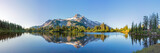 Fototapeta Natura - Volcanic mountain in morning light reflected in calm waters of lake. 