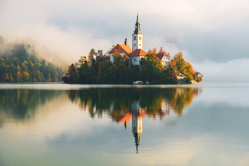 Famous Bled Lake in Triglav National Park in the Julian Alps with a forest in autumn colors at sunrise