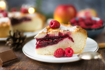 Delicious Christmas raspberry pie with berry filling and icing sugar and spices on a dark background.