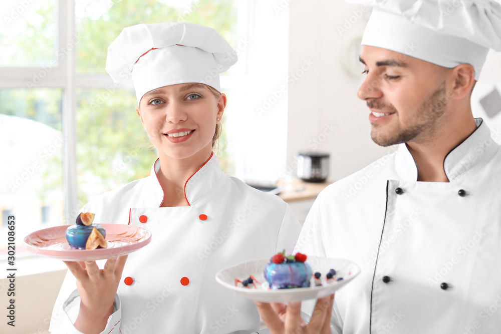Young confectioners with tasty desserts in kitchen