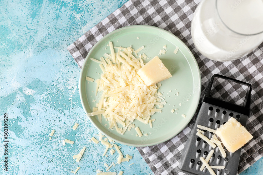 Plate with tasty Parmesan cheese and grater on table
