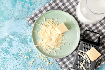 Plate with tasty Parmesan cheese and grater on table