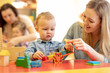© Oksana Kuzmina - Children with teachers playing with color wooden puzzle in a montessori classroom