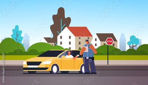 Fotomural police officer writing report parking fine or speeding ticket for woman sitting