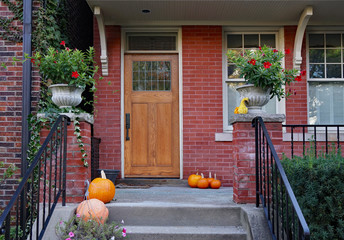 Front porch of older brick house with pumpkins and flower pots