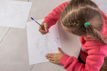 Girl draws at the table, view from the top