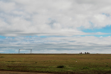 People riding horses in a vast landscape, moving towards a goal post, on a cloudy morning in Table Land, Panchgani, Maharashtra, India