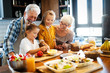 © NDABCREATIVITY - Happy senior couple having breakfast with their grandchildren at home
