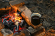 © Vlada - Black enamel cup of hot drink sitting on a stone by the fire in the open air. Focus on a mug with a blurred background.Detail of a camping, lifestyle while traveling. Hot coffee at the campsite