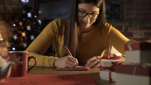 Woman Writing Wishes On A Christmas Card