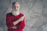 Fototapeta  - Photo of amazing aged grandpa guy indicating finger empty space advising new product wear red knitted pullover hipster santa role isolated grey color wall background