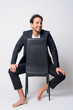 © Ranta Images - Full body shot of happy Hispanic businessman thinking while sitting on chair