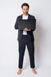 © Ranta Images - Full body shot of handsome Hispanic businessman using laptop
