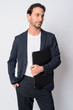 © Ranta Images - Portrait of handsome Hispanic businessman thinking while holding laptop