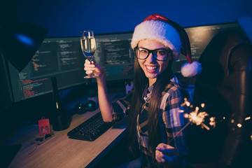 Photo of skilled it specialist business lady holding sparkling wine and fireworks at corporate company newyear party say toast best night wear santa cap glasses office indoors