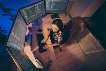 Above top high angle view photo of woman sitting before various monitors seriously looking into written code before implementation working on site back-end
