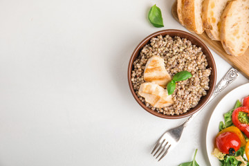 Tasty buckwheat porridge with meat on white table, flat lay. Space for text