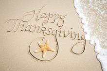 Happy Thanksgiving Message Handwritten On Smooth Sand Beach With Decorative Starfish And Oncoming Wave