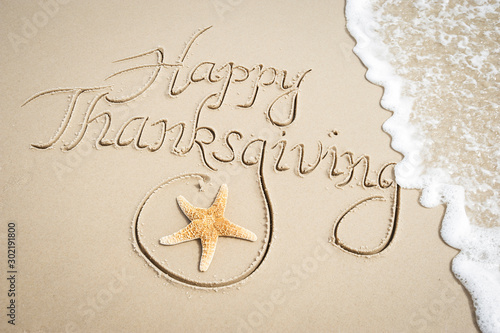 Fotomural Happy Thanksgiving message handwritten on smooth sand beach with decorative star