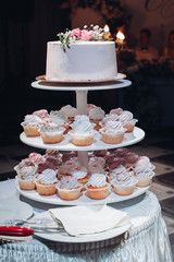 Wall Mural - Front view of beautiful wedding cake with flowers staying on table. Delicious dessert for celebration. Lovely pair at background. Concept of love, confectionery and biscuit.