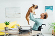 © LIGHTFIELD STUDIOS - Smiling disabled man holding up french bulldog in living room