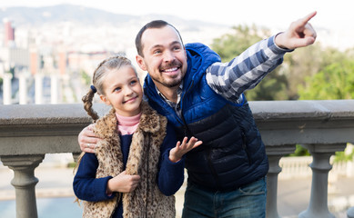 smiling father and daughter pointing at sight during sightseeing tour