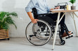 © LIGHTFIELD STUDIOS - Cropped view of man in wheelchair writing in notebook at workplace