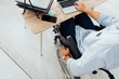 © LIGHTFIELD STUDIOS - Cropped view of man in wheelchair using laptop at workplace