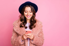 Photo Of Pretty Youngster Lady Hold Telephone Hands Reading Positive Comments Followers Wear Fluffy Jacket Retro Blue Hat Isolated Pink Background