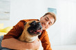 © LIGHTFIELD STUDIOS - Happy man hugging french bulldog in living room