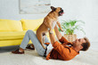 © LIGHTFIELD STUDIOS - Side view of man playing with french bulldog on carpet at home