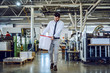 © Dusan Petkovic - Full length of handsome caucasian bearded graphic engineer carrying bucket with liquid glue. Printing shop interior. In background are printing machines.
