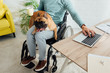 © LIGHTFIELD STUDIOS - Cropped view of disabled man with french bulldog on knees holding cup and working on laptop