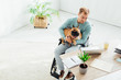 © LIGHTFIELD STUDIOS - Disabled man holding french bulldog and looking at laptop in living room