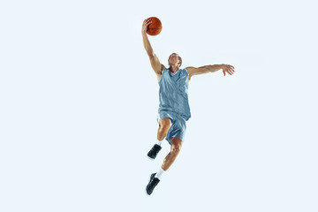 High flight. Young caucasian basketball player of team in action, motion in jump isolated on white background. Concept of sport, movement, energy and dynamic, healthy lifestyle. Training, practicing.