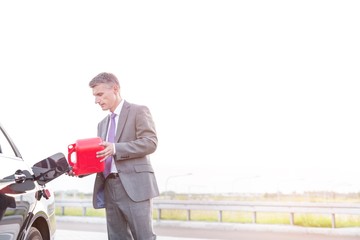 Wall Mural - Businessman refueling his car during busines trip