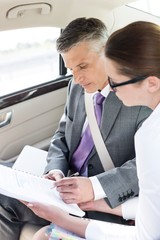 Wall Mural - Business people discussing plans over document inside the car during business trip